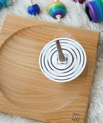 A Mader monochrome coloured disc placed on the so and so spinner. The spinner can be seen spinning in motion on a wooden spinning plate.