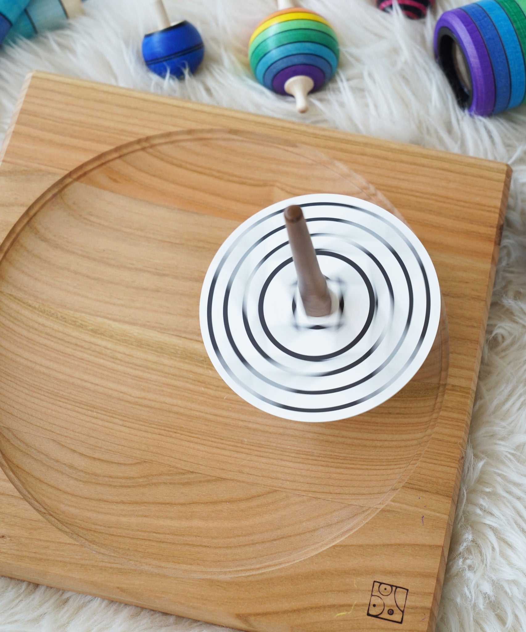 A Mader monochrome coloured disc placed on the so and so spinner. The spinner can be seen spinning in motion on a wooden spinning plate.