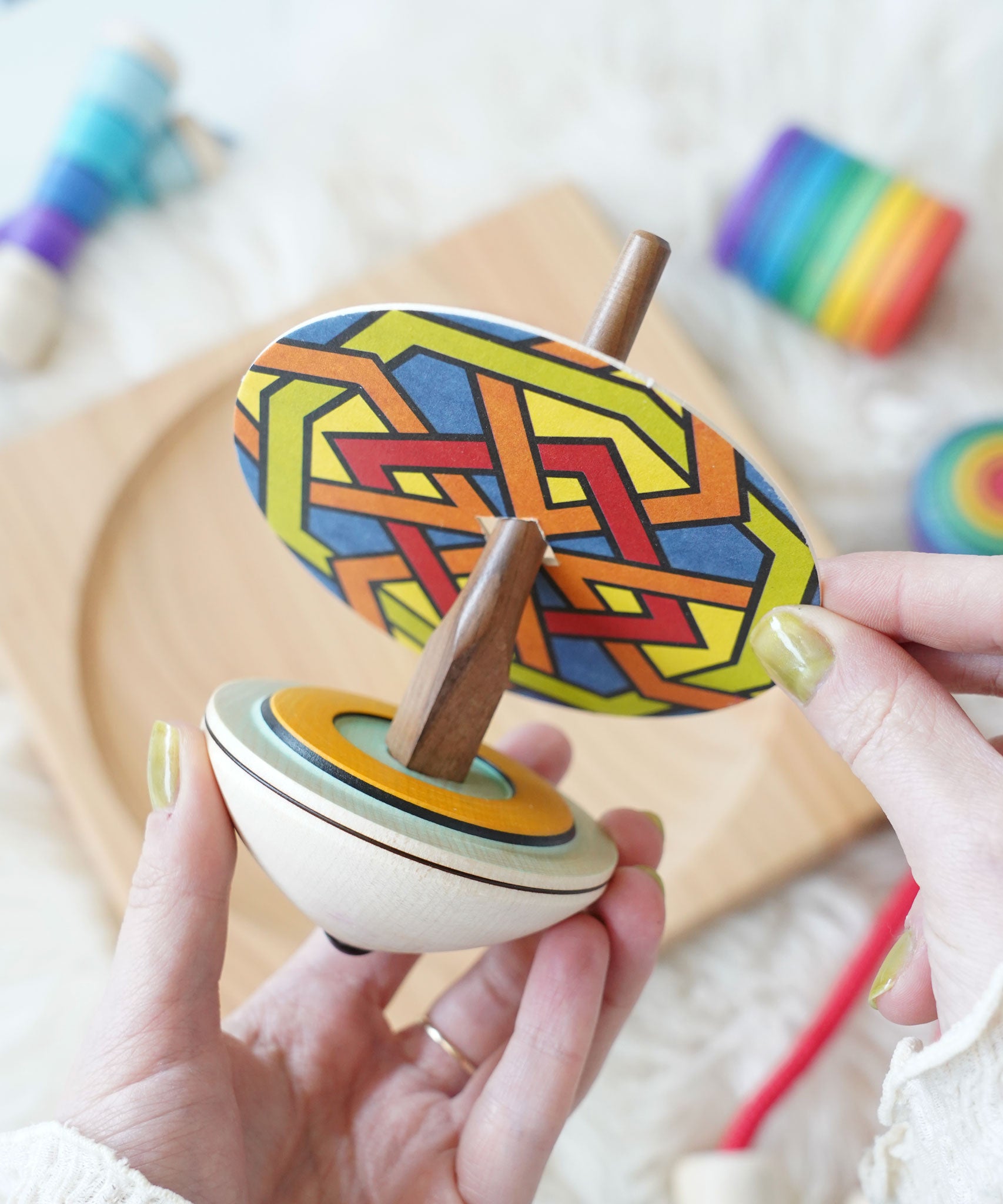 A cardboard disc being placed in the Mader So and So wooden spinning top set.