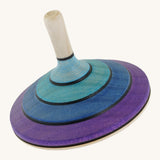 A wooden purple and blue flamenco Mader spinning top on a cream background.