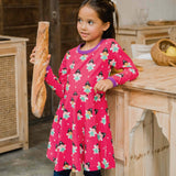 A child wearing the Maxomorra Fairy print circle dress. The child is holding a baguette and is leaning against a kitchen counter top