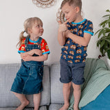 Boy and girl stood on a sofa wearing the Maxomorra short sleeve bulldozer top and tulip top