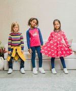 Three children wearing Maxomorra, the first is wearing stripes, the child in the middle is wearing a unicorn raglan top and the third child is wearing the Maxomorra Unicorn Long Sleeve Circle Dress.