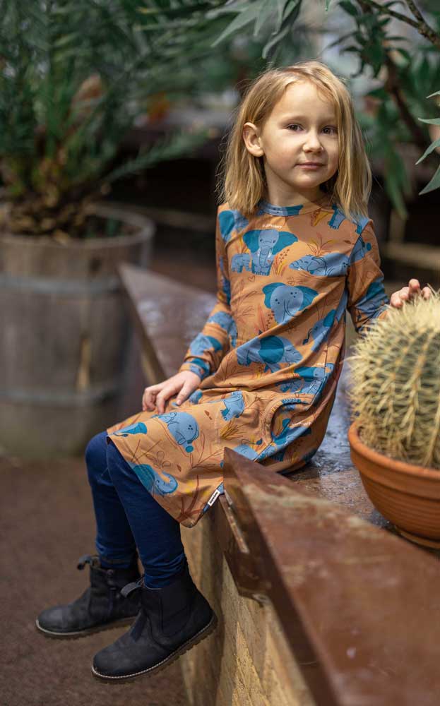 organic long sleeved dress in caramel brown with savannah and elephant repeat print. Worn by child