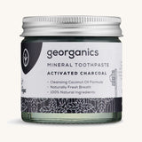 A jar of mineral activated charcoal toothpaste on a cream background