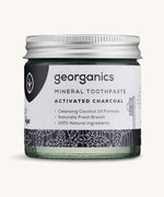 A jar of mineral activated charcoal toothpaste on a cream background