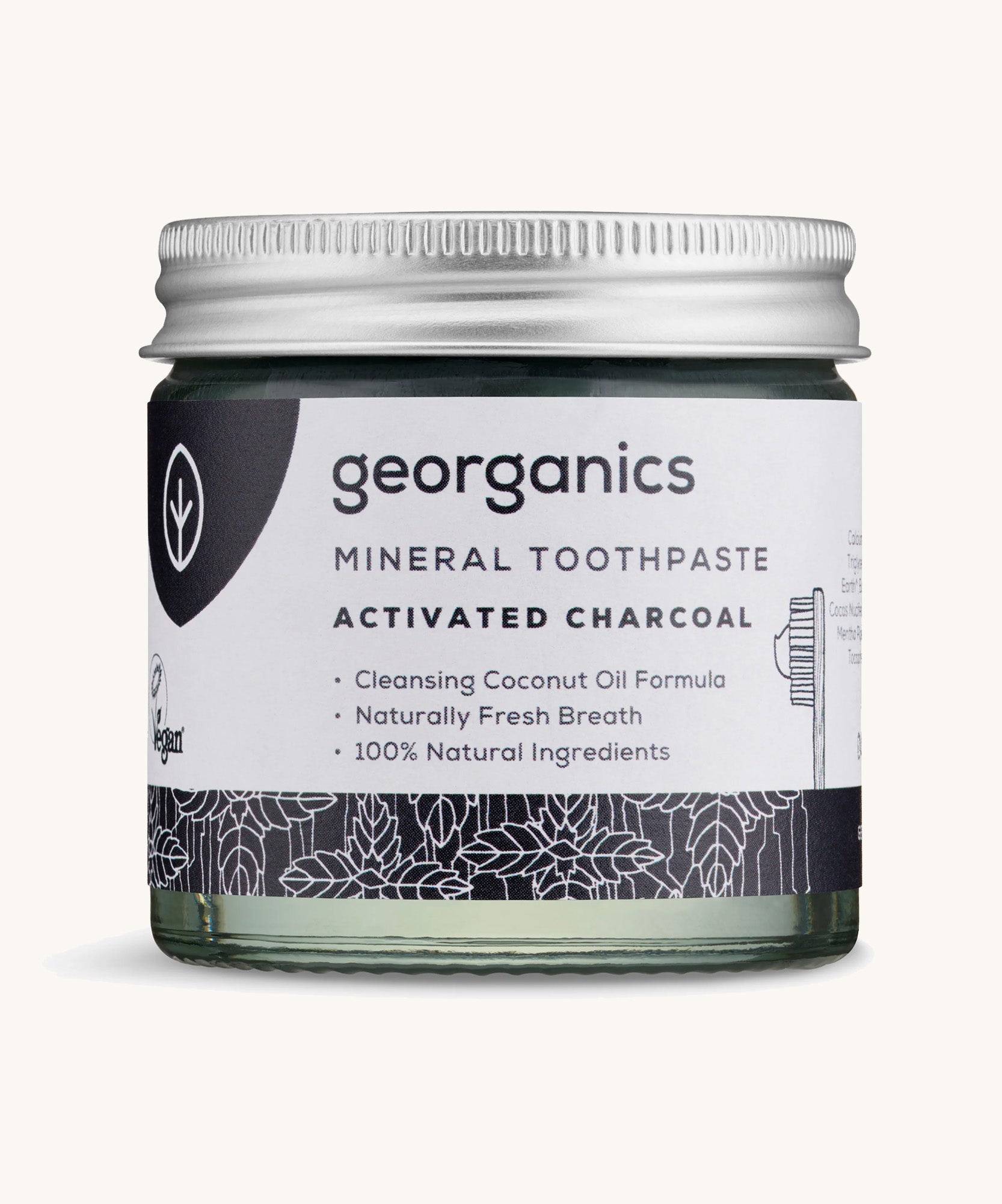 A jar of mineral activated charcoal toothpaste on a cream background