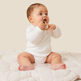 A baby sitting up and wearing the Mori organic kimono baby bodysuit in white.