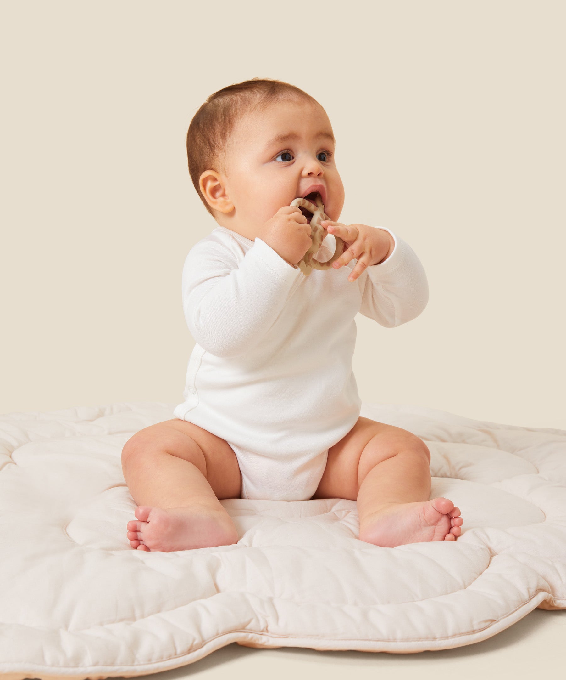 A baby sitting up and wearing the Mori organic kimono baby bodysuit in white.