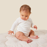 A baby wearing the Mori organic kimono baby bodysuit in white.