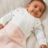 A close up of the MORI blush stripe baby swaddle showing the popper detail on the arms, to tuck the arms in or let them be free.