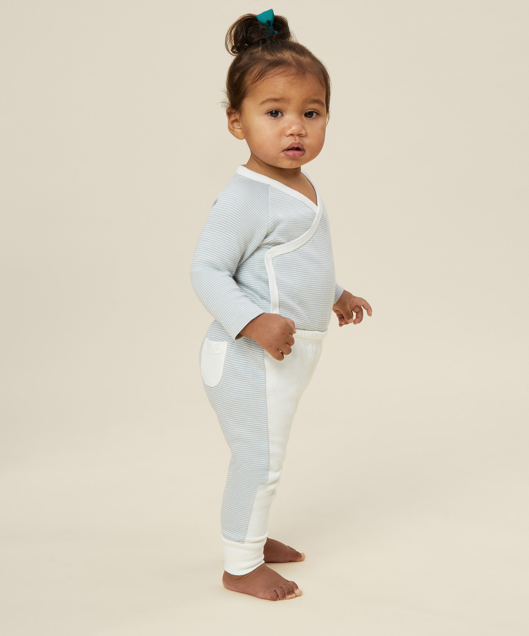 A toddler wearing the Mori organic cotton and bamboo kimono bodysuit in a blue stripe design.