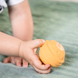 A childs hand holing the yellow ball from the Sophie The Giraffe - Once Upon A Time 5 Senses Musical Balls