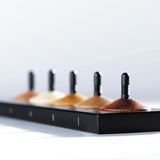 Close up of the the 5 Naef premium wooden spinning tops toy set on a white background