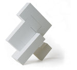 4 pieces of Naef's Quadrigo toy assembled to make a geometric shape titled diagonally.