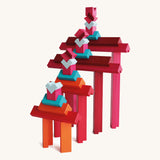Layered tower of Naef Tigno coloured wooden blocks in varying lengths and hues. High quality German made precision wooden toy for stacking and display.
