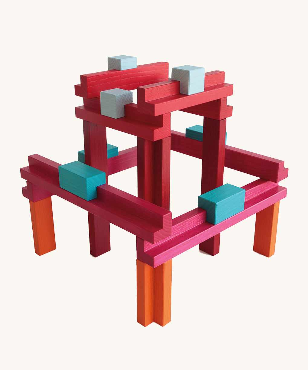 Brightly coloured Naef Tigno precision wooden stacking toy showing geometric construction in red, orange, blue, and pink blocks. Premium German made wooden puzzle and design object.