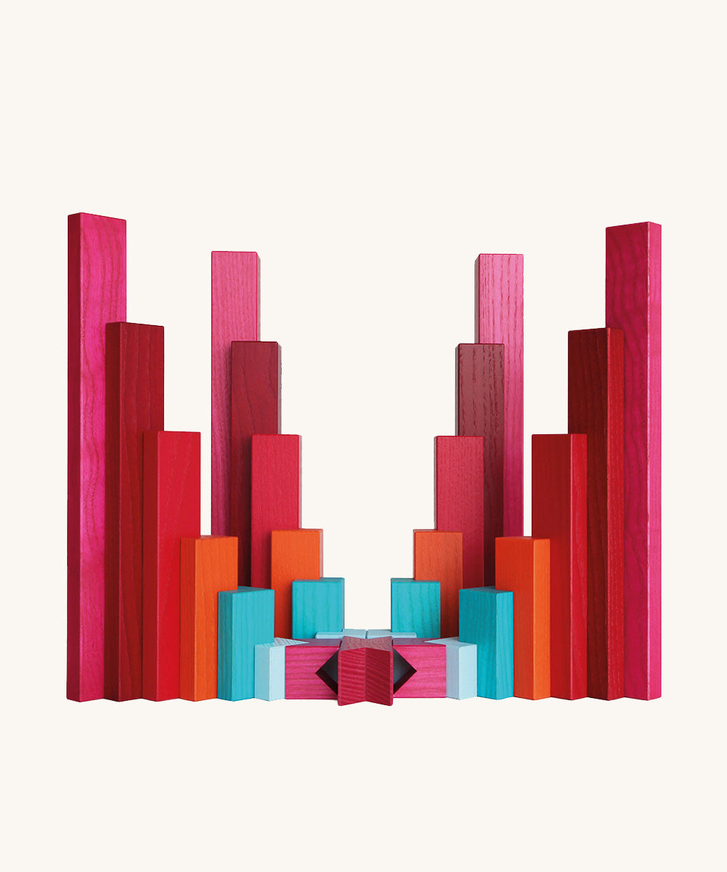 Symmetrical sculptural arrangement of Naef Tigno precision wooden blocks in red, pink, orange, and blue. Elegant German made stacking game and collectible desk toy.