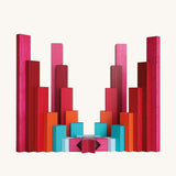 Symmetrical sculptural arrangement of Naef Tigno precision wooden blocks in red, pink, orange, and blue. Elegant German made stacking game and collectible desk toy.