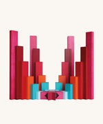Symmetrical sculptural arrangement of Naef Tigno precision wooden blocks in red, pink, orange, and blue. Elegant German made stacking game and collectible desk toy.