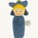 Nanchen Flower Rattle Doll - Forget-Me-Not, is a soft, organic and handmade sensory doll toy with a blue body, a little blue hat with blue forget-me-not leaves and a yellow strip of fabric to mimic hair. This doll also has an adorable face with blue eyes