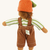 Back view of the same Nanchen organic Waldorf doll wearing the full outfit including the orange fruit hat with green leaf, showing the doll's wild brown hair and sewn-in brand tag.