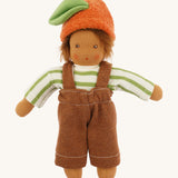 Front view of the dressed Nanchen organic Waldorf doll in green striped top, brown dungarees, and orange fruit hat with green leaf. The doll has brown skin and spiky brown hair.