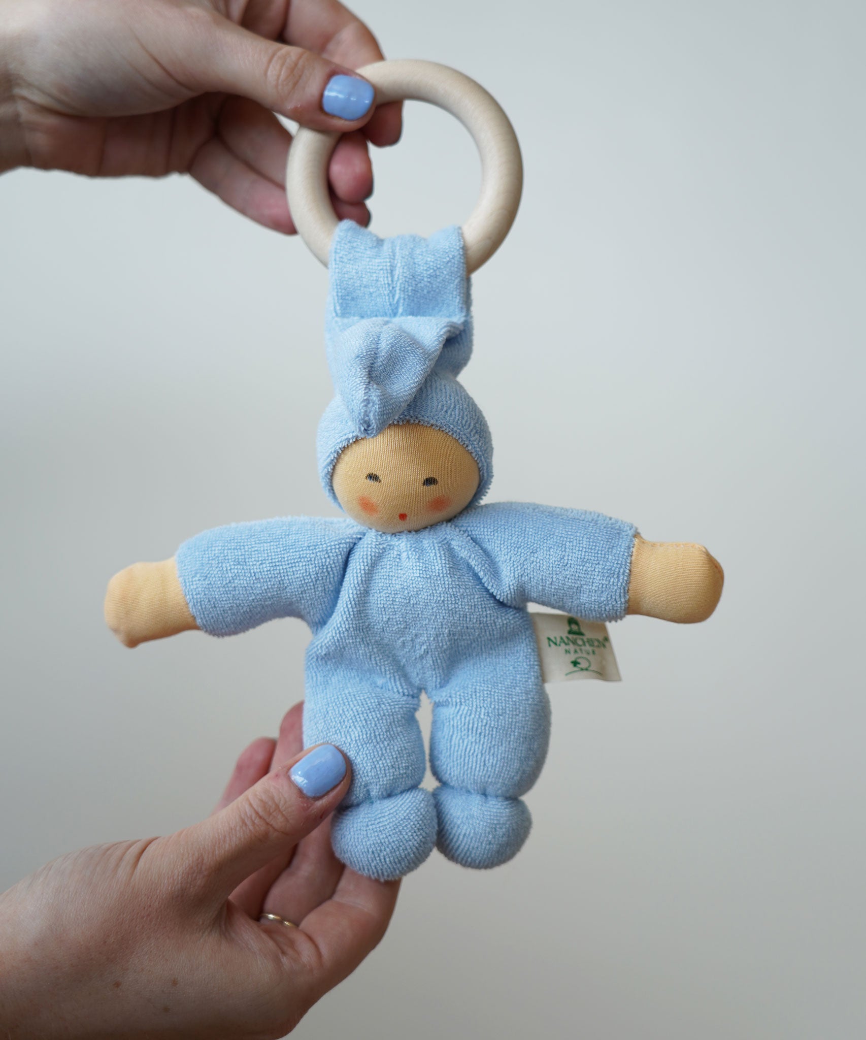 A light blue Nanchen Pimpel Waldorf Doll Ring Comforter toy being held in an adult's hands.