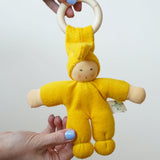 A close up of a yellow Nanchen pimpel doll in an adult's hand.
