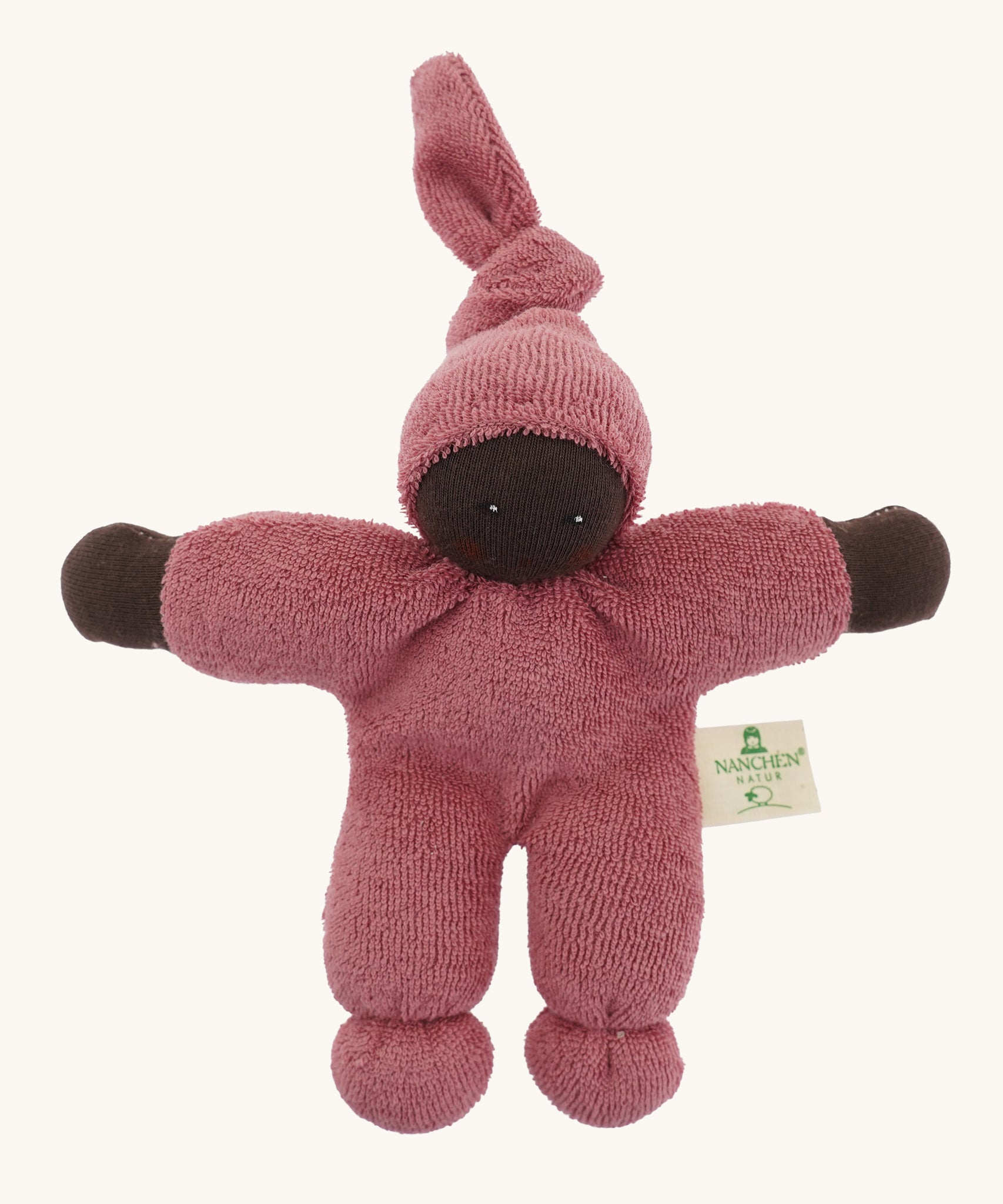 A Nanchen Pimpel Waldorf Handcrafted Doll with a berry pink coloured outfit an matching knotted hat. The doll has dark brown coloured skin.