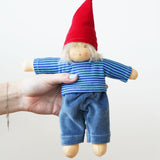 A Nanchen Frederik Waldorf Doll being held in an adult's hand. The doll has white blonde hair and is wearing a gnome inspired outfit.