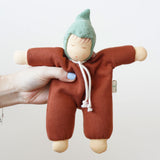 A close up of a Nanchen Walnut Baby Waldorf Doll in an adult's hand.