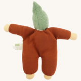 Back view of the Nanchen Walnut Baby Doll, displaying its rust-colored cotton terry body and knitted green pointed hood. The doll’s arms are outstretched and the natural cotton tag is visible on the side.