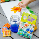 The Natural Earth Paint Petite Paint Kit in use. A child's hand can be seen in the background painting a picture of a daffodil.