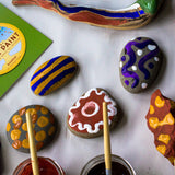 Close up of some pebbles painted with the Natural Paint kit in some colourful patterns