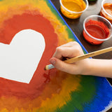 Close up of child's hand painting and rainbow heart with the Natural Earth kids eco-friendly paint set