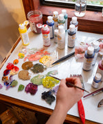 An artist using different Natural Earth Paint acrylic paints mixing different colours on a glass surface.
