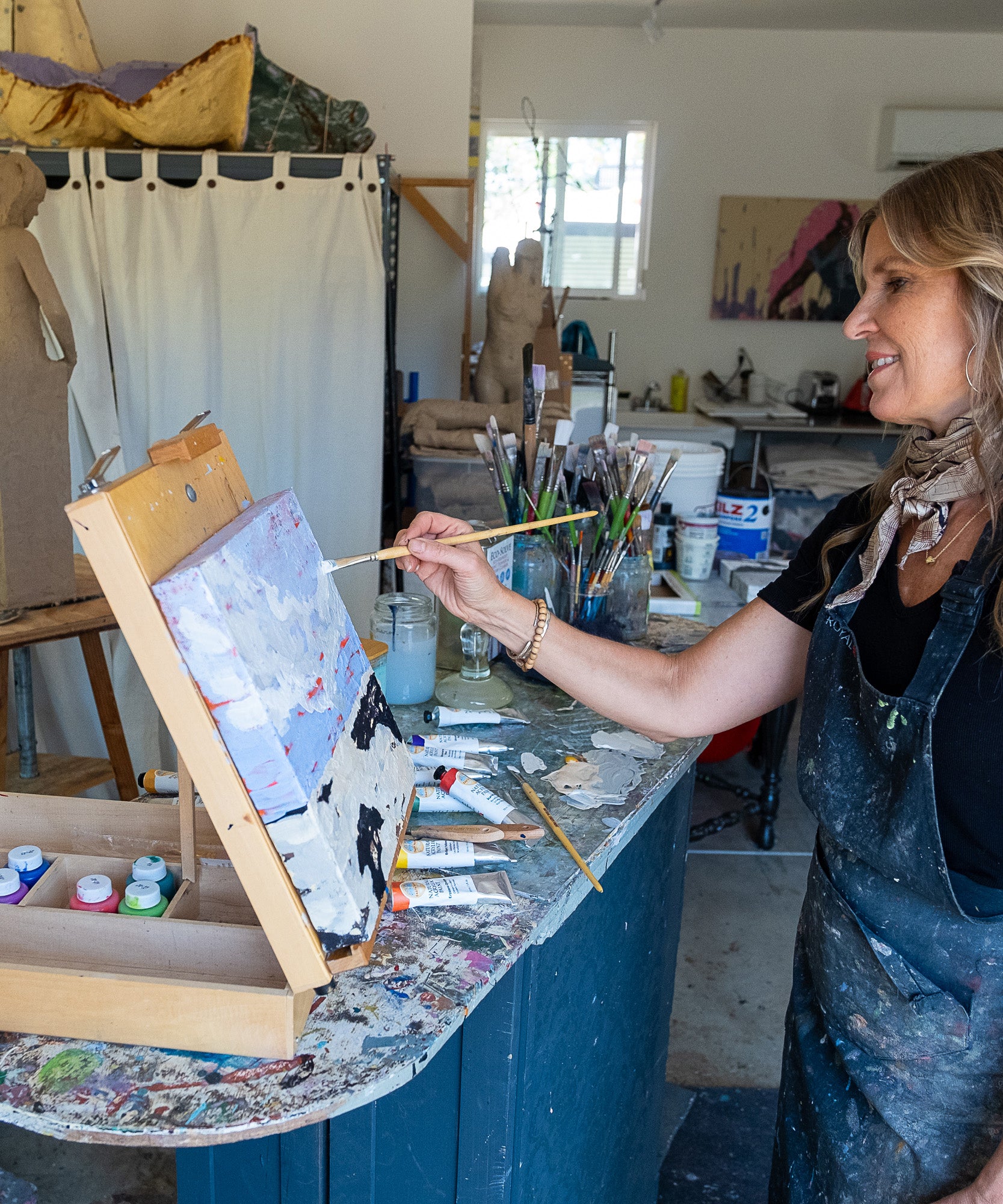 An artist in the studio painting on a canvas using the Natural Earth Pain natural acrylic paints