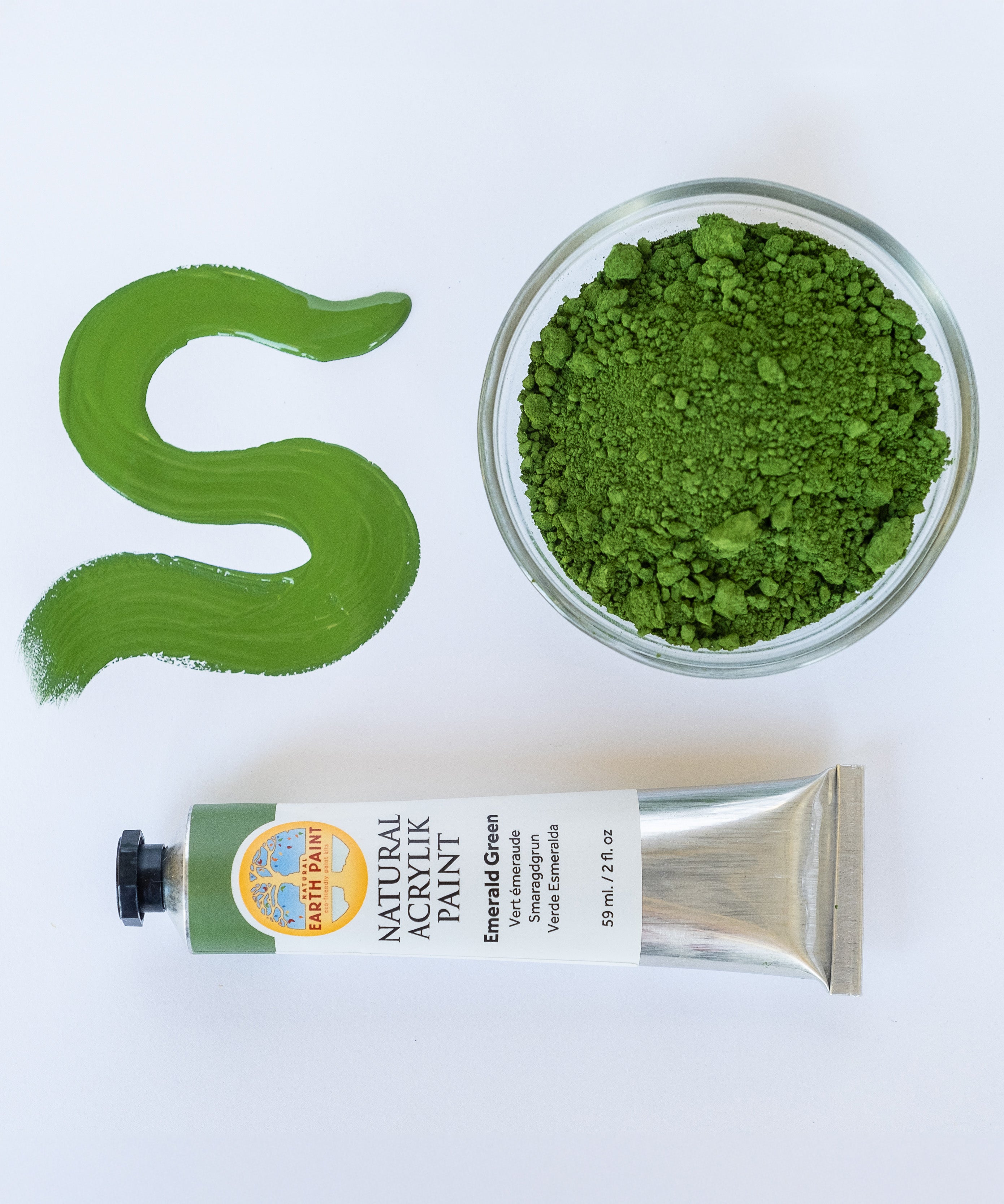A top down view of the Natural earth paint tube in emerald green next to a bowl of matching paint pigment and a streak showing the consistency.