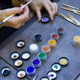 Close up of some hands painting with the Natural Earth kids coloured face paint jars on a grey table