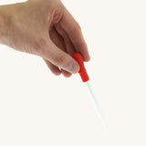 A adult hand holding the Natural Earth Paint glass dropper by the red squeeze handle for size reference