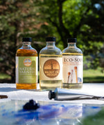 Natural Earth Paint natural varnish next to the walnut oil jar and brush cleaner on a table in the garden