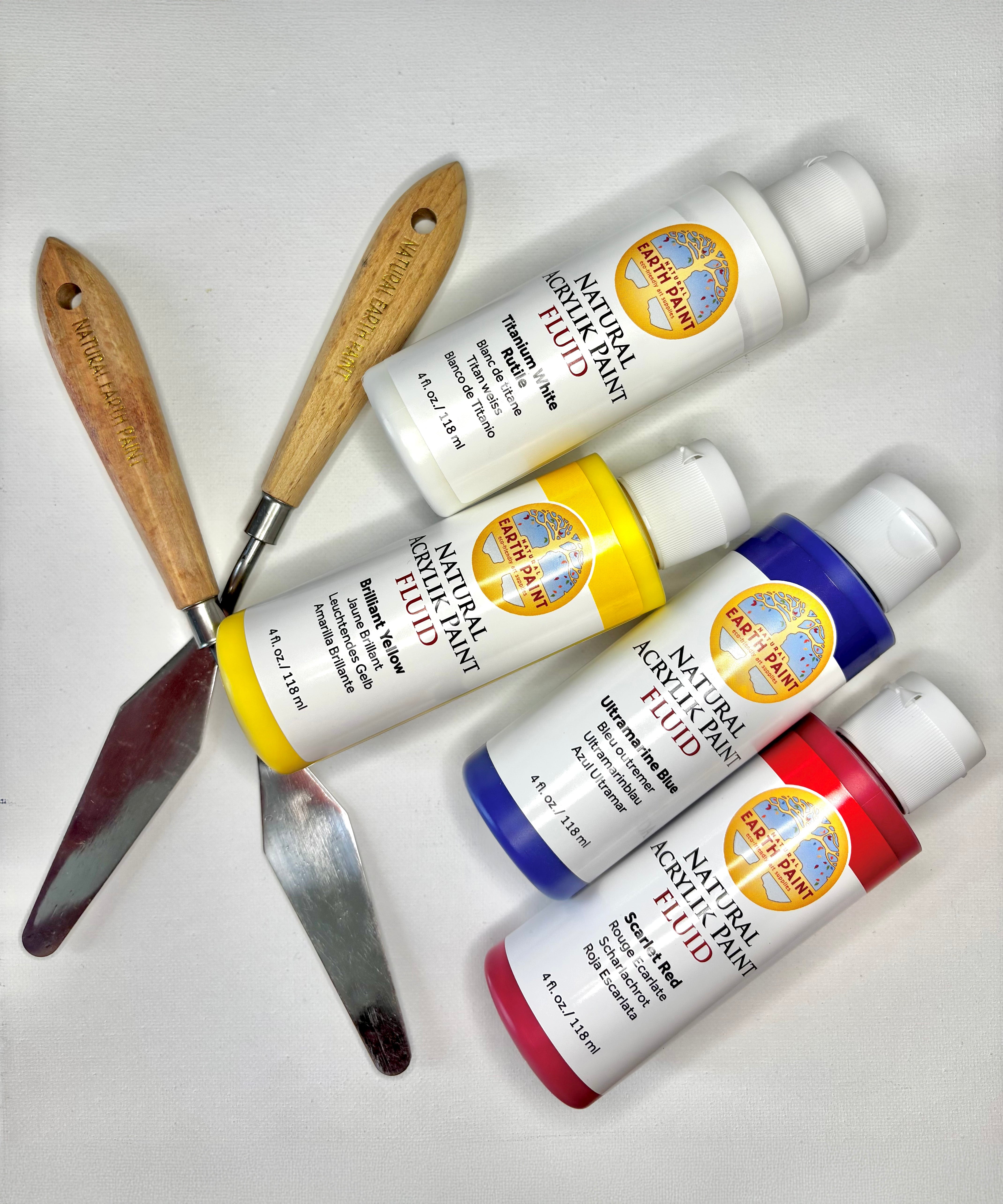Natural Earth Paint palette knife with wooden handle laid next to white, yellow blue and red acrylic paint
