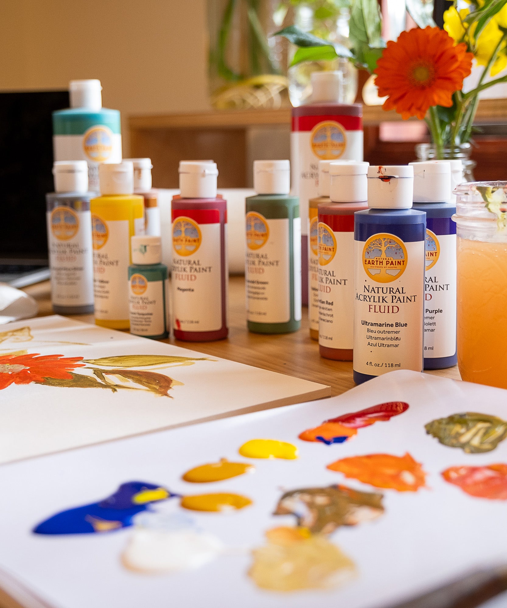 Natural Earth Paint acrylic set on a wooden surface with samples on a paper