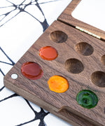 A close up of the Natural Earth Paint small wooden watercolour palette showing different coloured paint in the well