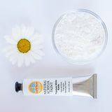 A top down view of the Natural earth paint in titanium white next to the white pigment powder and a white daisy flower