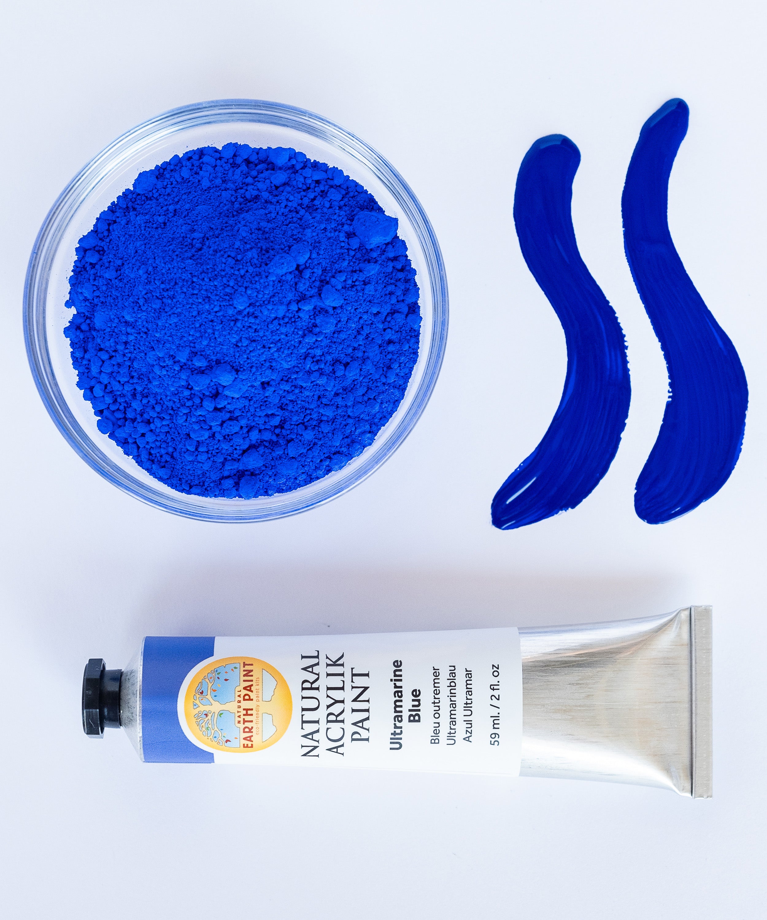 A top down view of the Natural earth paint in ultramarine blue next to the blue pigment powder and 2 streaks showing the consistency.