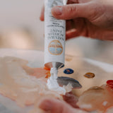 An artist hand squeezing the aluminium tube with white natural acrylic paint coming out from it