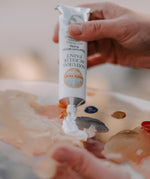 An artist hand squeezing the aluminium tube with white natural acrylic paint coming out from it