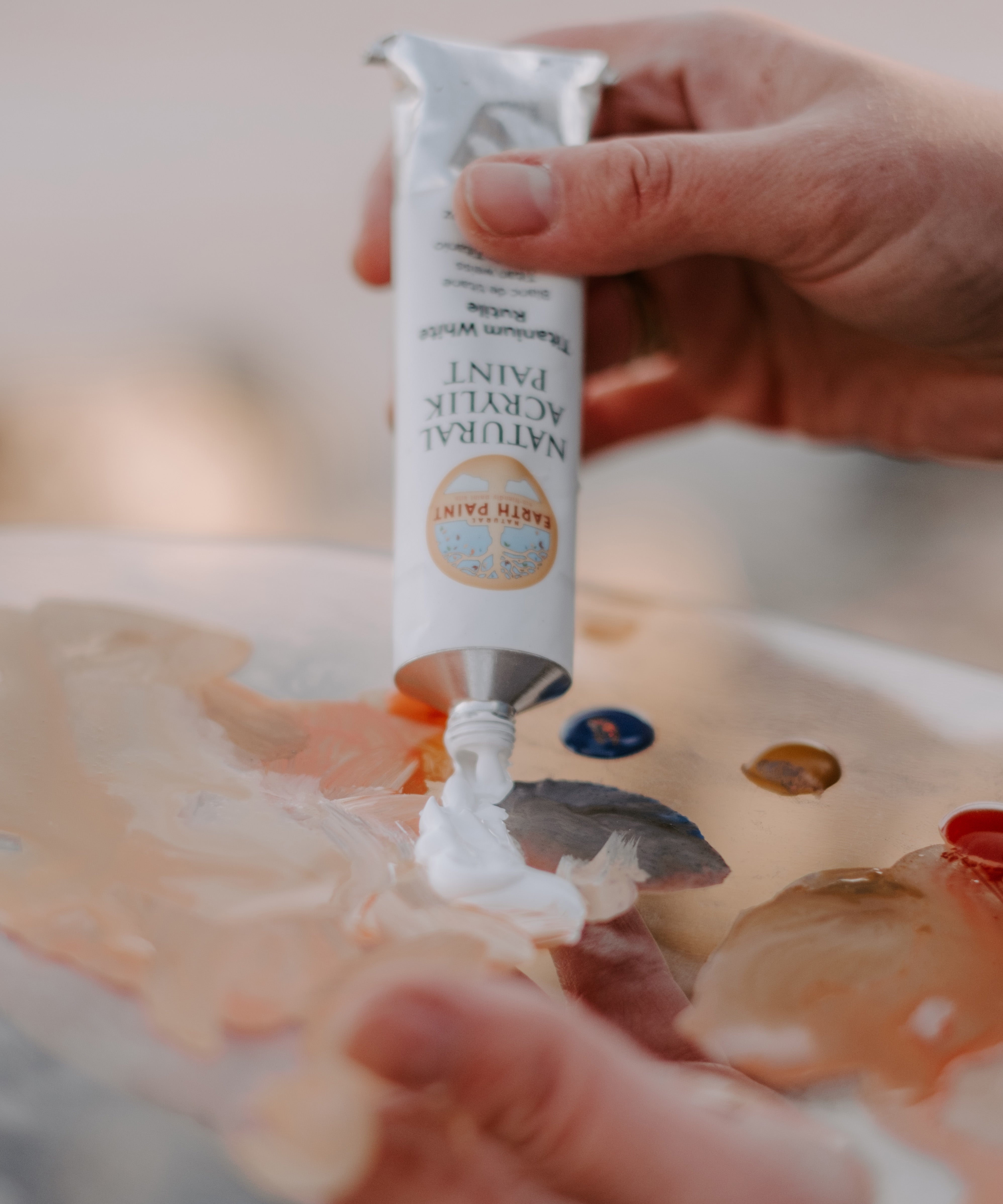 An artist hand squeezing the aluminium tube with white natural acrylic paint coming out from it